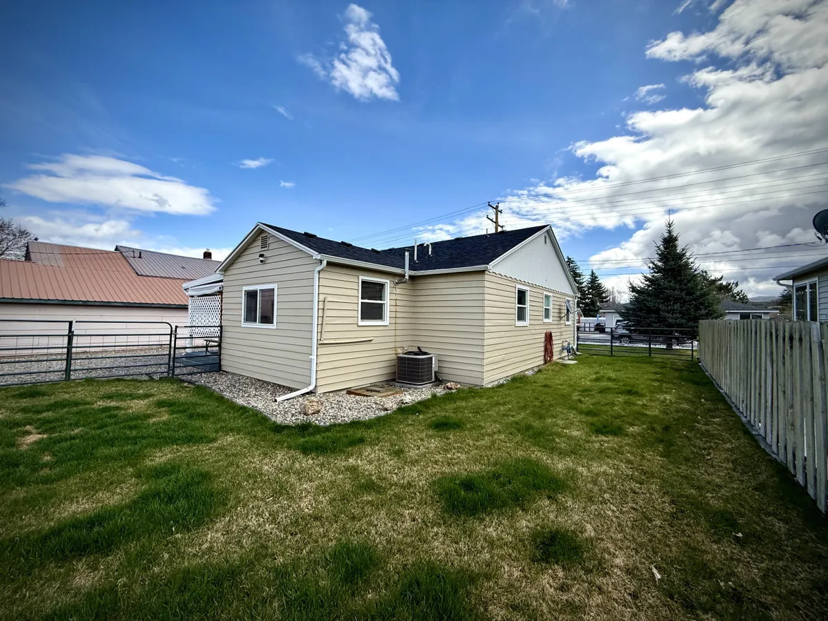 The exterior of the home showcases a spacious grassy yard bordered by a sturdy fence—ideal for pets and outdoor gatherings. The inviting setting hints at the backyard firepit mentioned in the section.