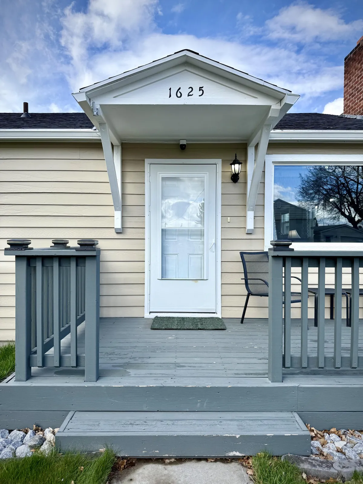 A welcoming exterior shot of the home's front door and porch, featuring a chair and attractive lighting fixture. The inviting porch suggests a cozy spot for morning coffee or evening relaxation.