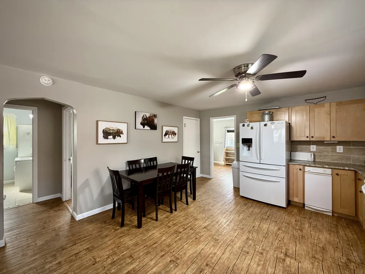 A cozy dining area that centers on a dining table surrounded by chairs, with the kitchen visible in the background. Details like wall art and cabinetry add warmth, and the layout encourages social meals and togetherness.