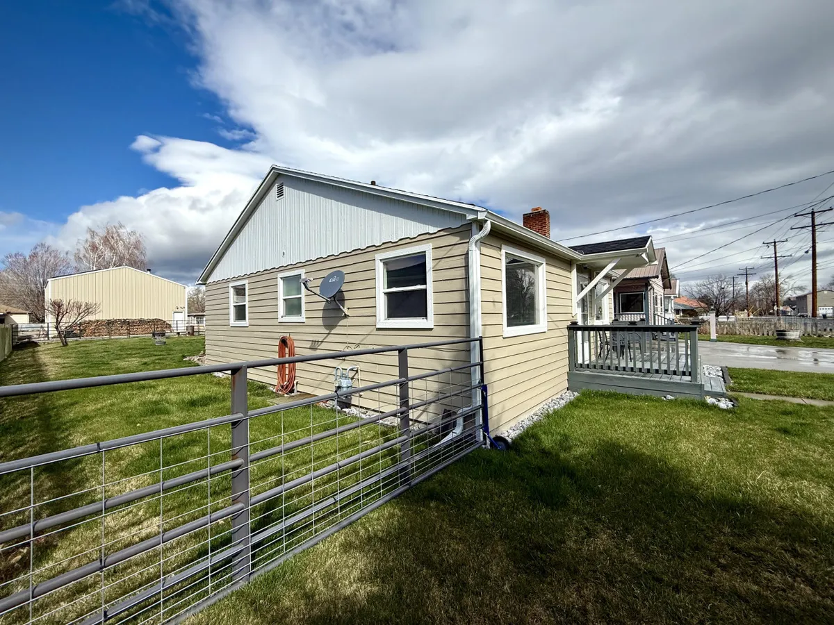 This image features the exterior of the house and highlights the fenced yard, a welcoming porch, and the overall inviting nature of the backyard space. The image shows plenty of room for activities like gardening or hosting gatherings.