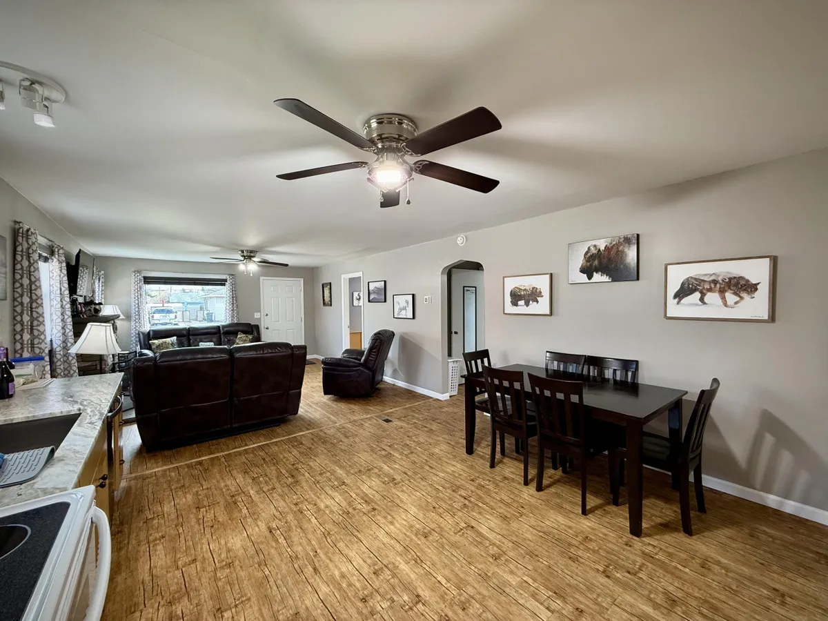 A view of the living room seating area extending to a dining table, with wildlife wall art adding a touch of character. The space is illuminated by soft natural light, inviting both relaxation and social meals.