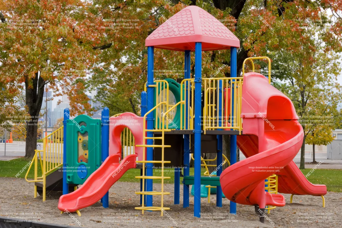 A vibrant, colorful playground structure is the focal point, complete with slides and climbing areas. The area is clearly designed for children, with soft surfaces and plenty of space around the play equipment, and a sense of energy as families gather for fun and play.